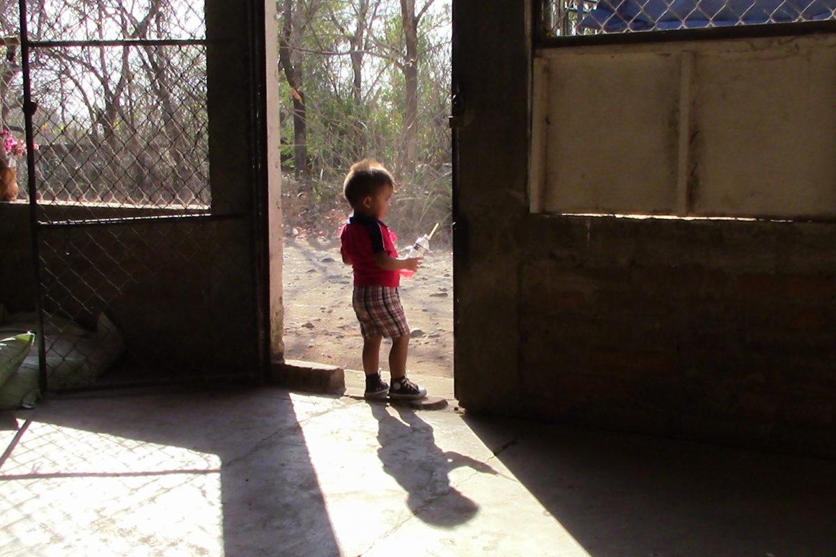 Photograph of a 3 year old boy standing in a doorway.