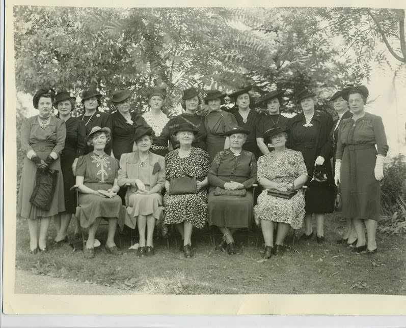 Old photograph of women dressed in victorian clothing, posing in two rows..