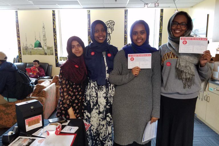 Photograph of four young women wearing headscarves holding up signs that say "I voted"