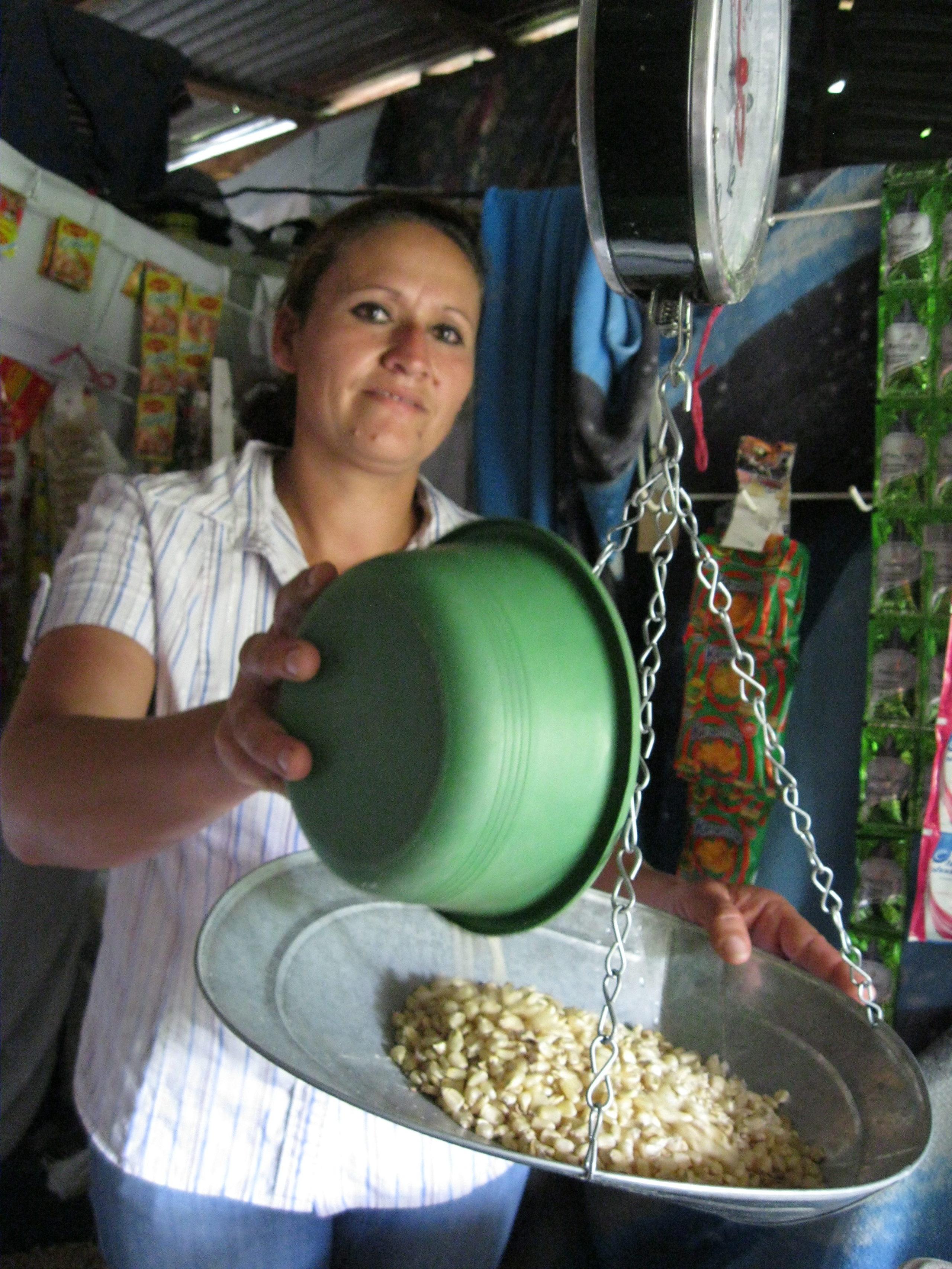 Image of a woman weighing grain in a scale in her home.