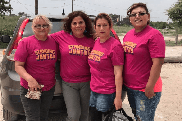 Group of four women wearing pink tshirts that say "standing juntas"
