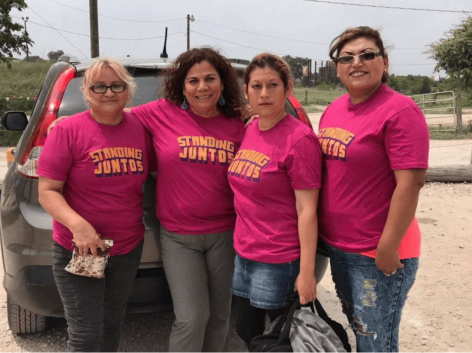 Group of four women wearing pink tshirts that say "standing juntas"