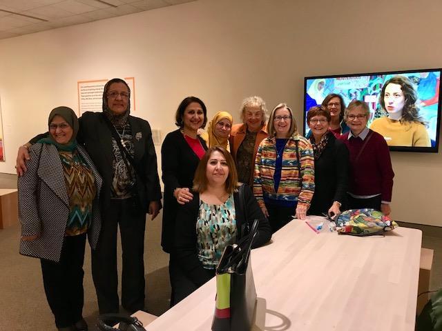 A group of Iraqi and American women stand together, some with their arms around one another.