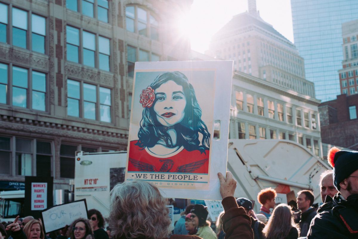 Photograph of a sign at a protest that features a latina woman with the phrase "we the people"