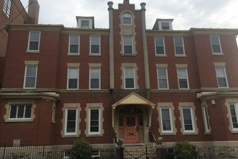 Photograph of outside of a brick apartment building.