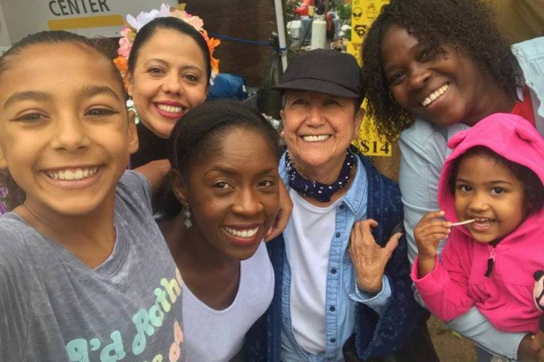 Close up photo of smiling faces of four women and two young girls.