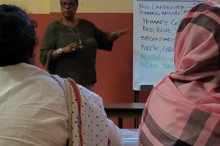 photograph of woman teaching with two students from the back.