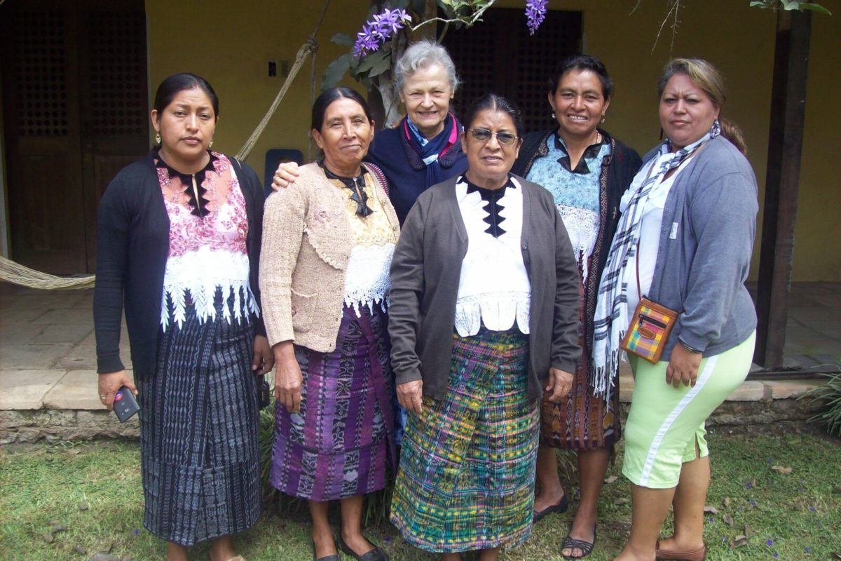 Photograph of several guatemalan woman in traditional dress, one woman from El Salvador, and one woman from the United States.