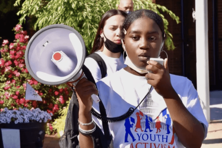 Young woman using megaphone at protest with Mary's Pence Grantee Youth Activism Project